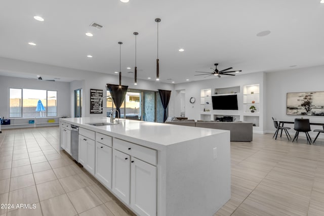 kitchen featuring ceiling fan, decorative light fixtures, built in features, a center island with sink, and white cabinetry