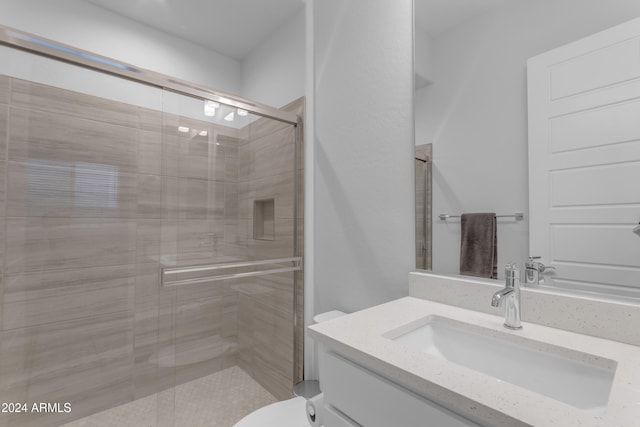 bathroom with a shower with door, vanity, and toilet