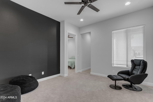 sitting room with ceiling fan and light colored carpet