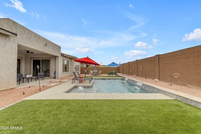 view of pool with pool water feature, ceiling fan, a yard, and a patio