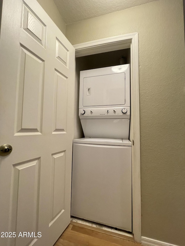 19400 N Westbrook Pkwy Unit 216, Peoria, AZ 85382 - laundry room with laundry area, stacked washer / drying machine, a textured wall, and wood finished floors