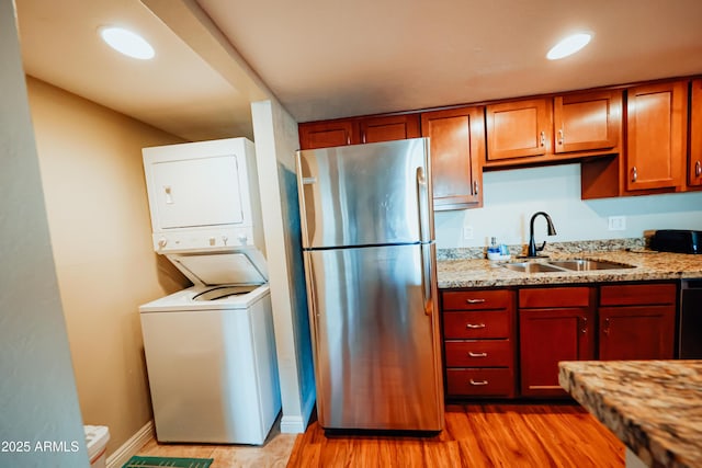 1645 W Baseline Rd Unit 2026, Mesa, AZ 85202 - kitchen with freestanding refrigerator, stacked washer and clothes dryer, light stone countertops, light wood-style flooring, and dishwasher