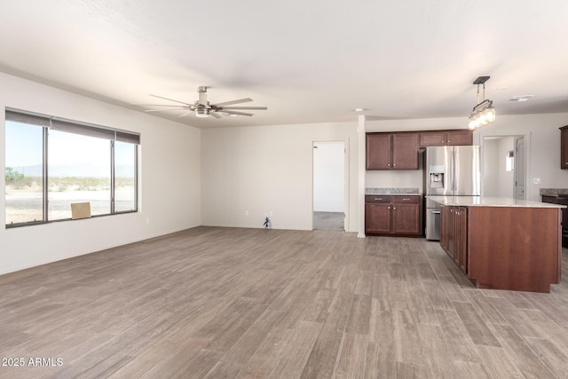 31515 W Buchanan St, Buckeye, AZ 85326 - kitchen featuring stainless steel refrigerator with ice dispenser, light wood finished floors, ceiling fan, open floor plan, and decorative light fixtures