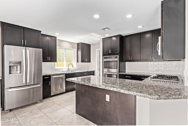 kitchen with visible vents, light stone countertops, light tile patterned floors, stainless steel appliances, and a sink