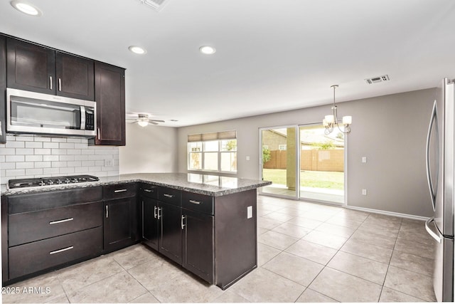 kitchen with visible vents, stone counters, a peninsula, stainless steel appliances, and backsplash