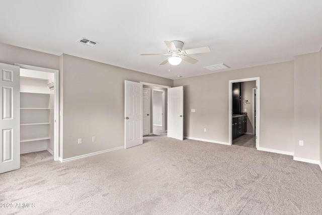 unfurnished bedroom featuring a spacious closet, carpet, visible vents, and baseboards