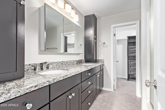 bathroom featuring a sink, baseboards, double vanity, and tile patterned flooring