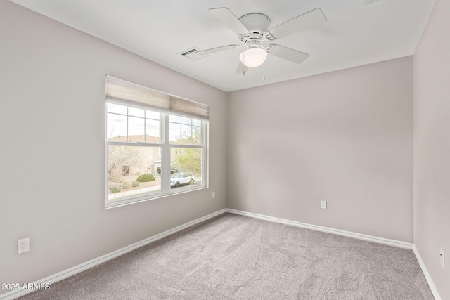 carpeted empty room with visible vents, baseboards, and a ceiling fan