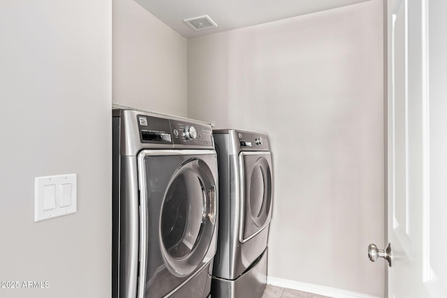 washroom with visible vents, washer and clothes dryer, tile patterned flooring, baseboards, and laundry area