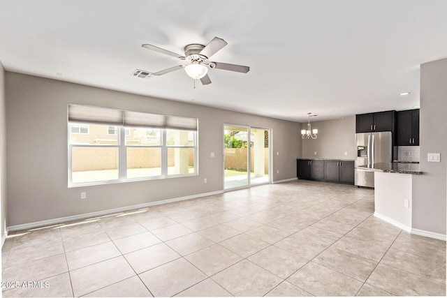 unfurnished living room featuring light tile patterned flooring, ceiling fan with notable chandelier, visible vents, and baseboards