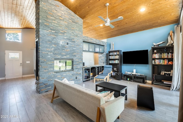living area with high vaulted ceiling, wooden ceiling, ceiling fan, and a stone fireplace