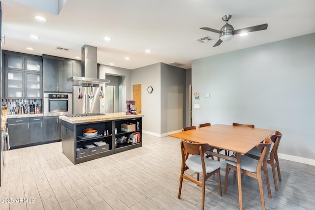 dining room featuring baseboards, a ceiling fan, light wood-style flooring, and visible vents