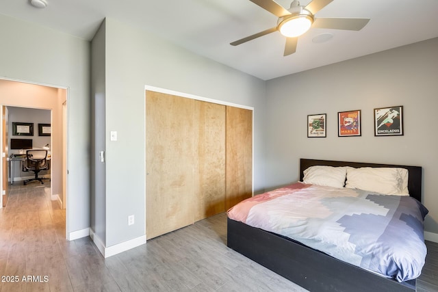 bedroom featuring baseboards, ceiling fan, wood finished floors, and a closet