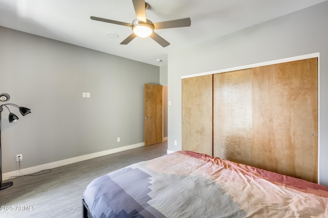 bedroom with a closet, a ceiling fan, baseboards, and wood finished floors