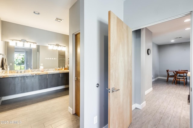corridor featuring visible vents, recessed lighting, baseboards, and wood finished floors