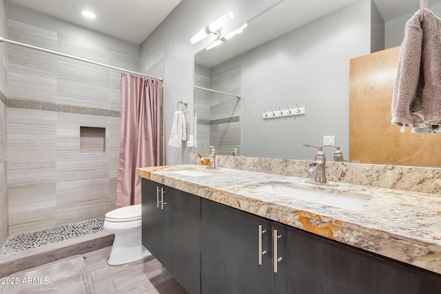 bathroom with double vanity, a sink, toilet, and a shower stall