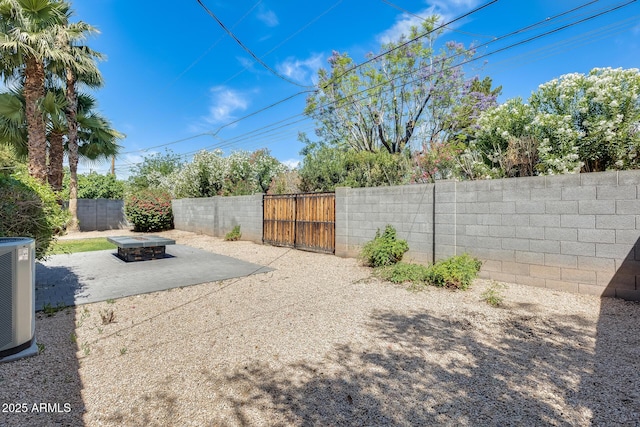 view of yard with central air condition unit, a gate, a fenced backyard, and a patio area