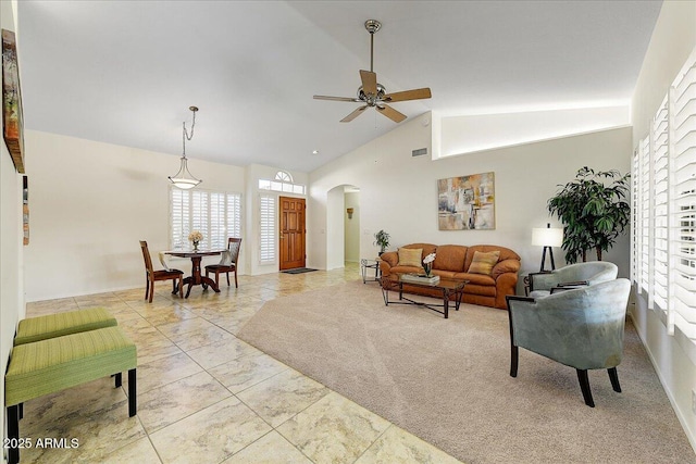 tiled living room with ceiling fan and high vaulted ceiling