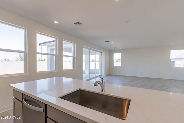 kitchen featuring light stone counters, sink, and stainless steel dishwasher