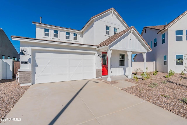 view of front facade featuring fence, an attached garage, concrete driveway, a tile roof, and board and batten siding