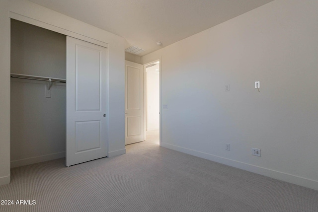 unfurnished bedroom featuring a closet and light carpet