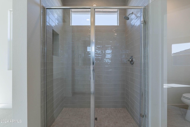 bathroom featuring a shower with door and toilet