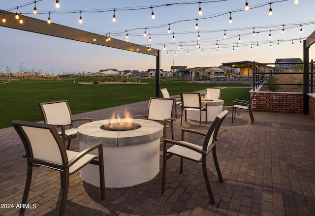 patio terrace at dusk featuring a yard and a fire pit