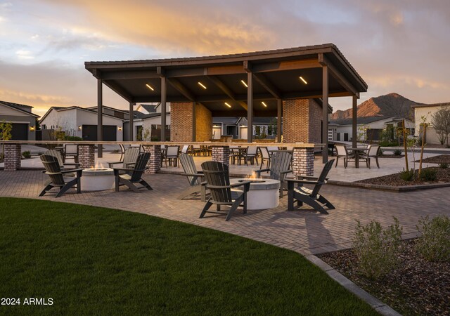 patio terrace at dusk with an outdoor fire pit and a lawn