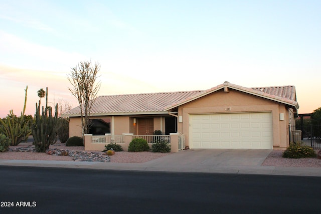 ranch-style home featuring covered porch and a garage