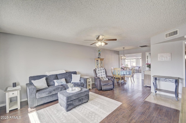 living room featuring ceiling fan, a textured ceiling, and dark hardwood / wood-style flooring