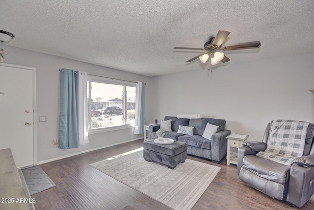 living room with a textured ceiling, dark wood-type flooring, and ceiling fan