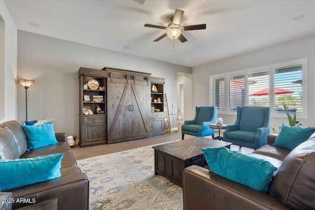 living room with a barn door and ceiling fan