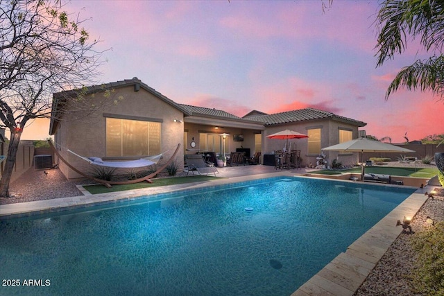 outdoor pool with a patio area, central air condition unit, and fence