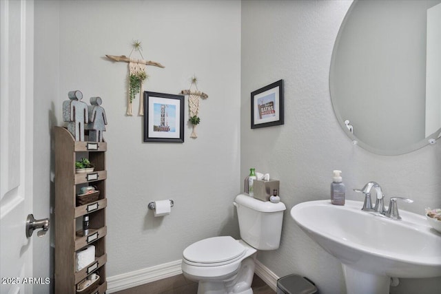 bathroom featuring a sink, baseboards, and toilet