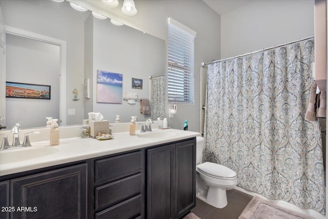 bathroom with a sink, toilet, double vanity, and tile patterned flooring