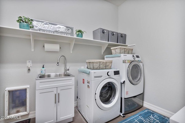 laundry area with washing machine and clothes dryer, cabinet space, baseboards, and a sink