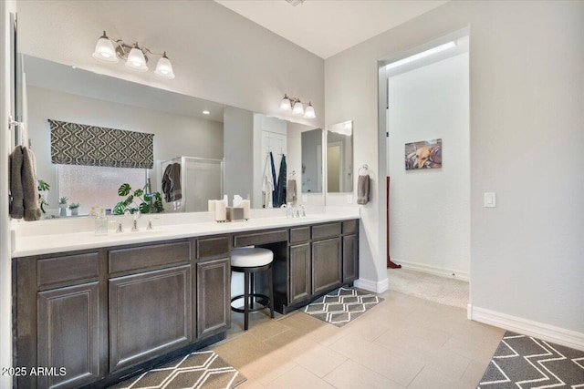 bathroom featuring double vanity, baseboards, and a sink