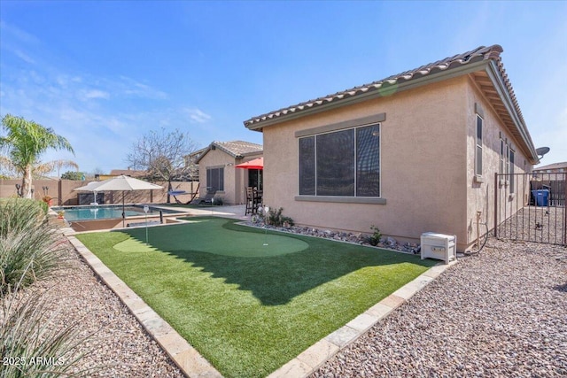 back of house with stucco siding, a patio, a fenced backyard, a fenced in pool, and a tiled roof