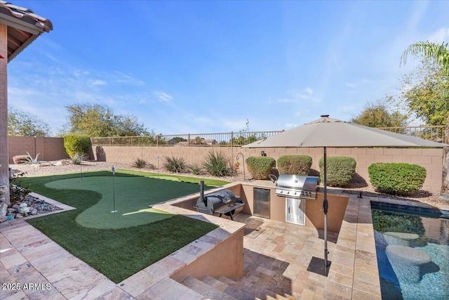 view of yard with a patio area, a fenced backyard, and an outdoor kitchen