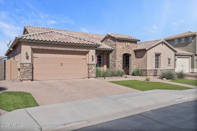 mediterranean / spanish home with stone siding, stucco siding, decorative driveway, and a garage