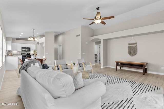 512 W Encinas St, Gilbert, AZ 85233 - living area with vaulted ceiling, a ceiling fan, light wood-style flooring, a chandelier, and arched walkways