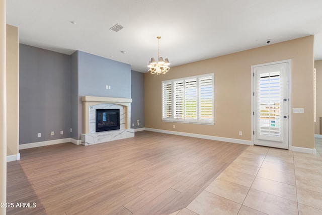 unfurnished living room featuring a notable chandelier, a fireplace, and light hardwood / wood-style floors