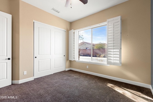 unfurnished bedroom with a closet, ceiling fan, and dark colored carpet