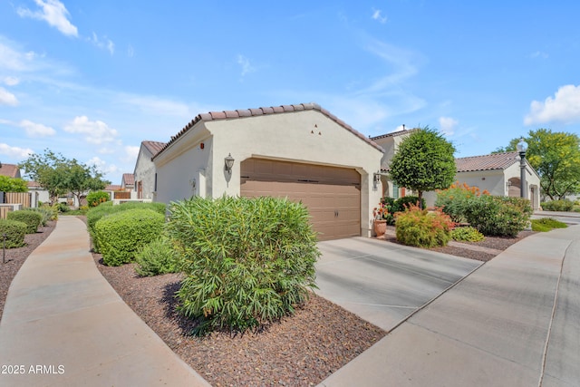 14200 W Village Pkwy Unit 2128, Litchfield Park, AZ 85340 - view of home's exterior featuring a garage, driveway, stucco siding, and a tile roof