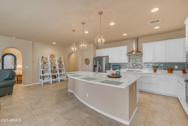 14200 W Village Pkwy Unit 2128, Litchfield Park, AZ 85340 - kitchen with wall chimney exhaust hood, stainless steel refrigerator with ice dispenser, arched walkways, decorative backsplash, and light countertops