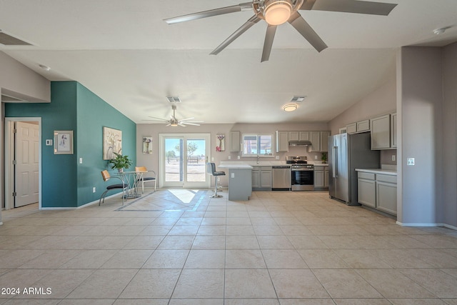 kitchen featuring lofted ceiling, gray cabinets, light tile patterned floors, and appliances with stainless steel finishes