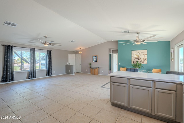 kitchen featuring gray cabinetry, a healthy amount of sunlight, light tile patterned flooring, and lofted ceiling