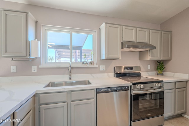 kitchen featuring light stone countertops, sink, light tile patterned flooring, and stainless steel appliances