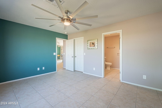 unfurnished bedroom featuring ceiling fan, a closet, light tile patterned flooring, and ensuite bathroom