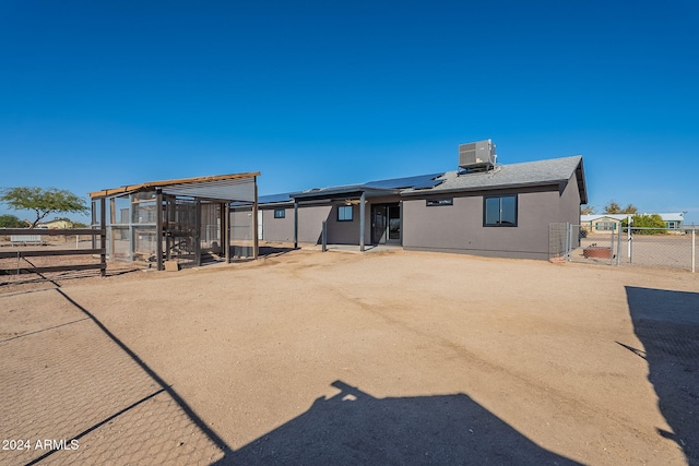 rear view of house with an outbuilding, solar panels, and cooling unit